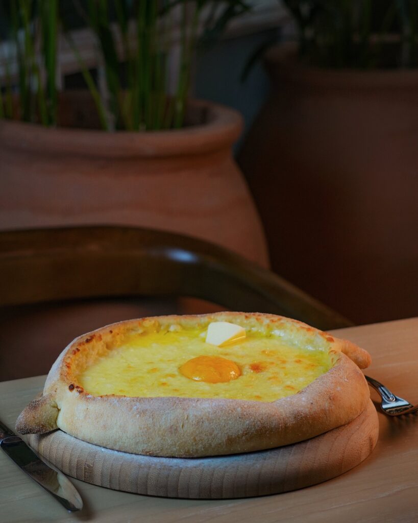 Adjarian khachapuri with egg yolk and butter on a wooden board, Vakhtanguri restaurant, Tbilisi
